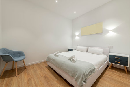 Bedroom with a king size bed with a white duvet, white bedside tables with blue drawers and a blue...