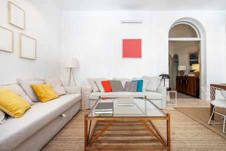 Living room with gray sofas with a wood and glass coffee table and natural fiber rugs and a...