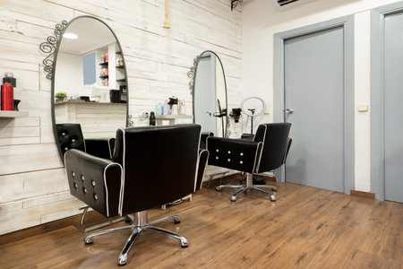 Hair cutting chairs with large oval mirrors on the wall in a traditional barbershopのeditorial素材