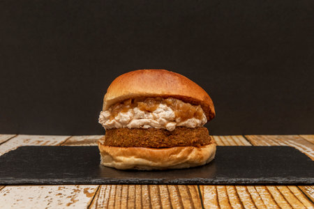 Vegan steak burger with pea cream and caramelized onions on black slate plateの写真素材