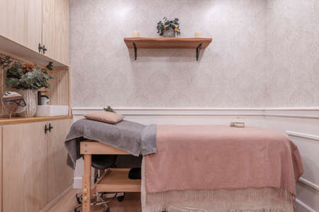 Folding wooden table covered with a tablecloth in a beauty salon booth with light pine furniture and shelving and eucalyptus branchesの写真素材