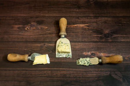 Special brie and blue cheese knives on a reddish wooden tableの写真素材