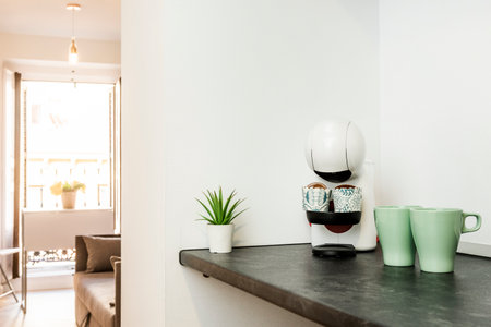 Living room with a black countertop with a pod coffee machine and two green porcelain pitchersの写真素材