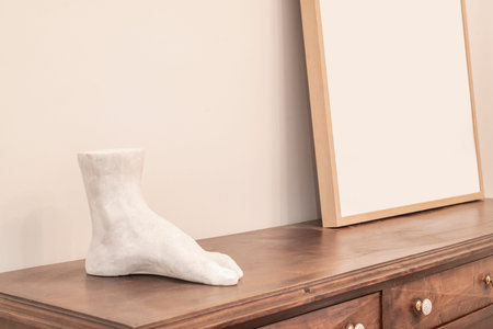 Wooden sideboard with a wooden frame on the top and a marble figure of a left foot