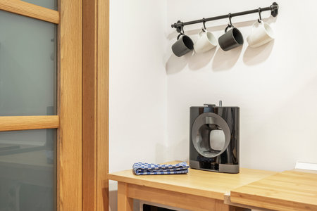 Corner of a kitchen with a solid wood table with a capsule coffee machine with gray and white porcelain cupsの写真素材
