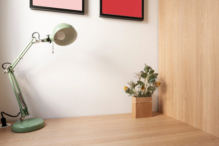 Corner of a room with a wooden wardrobe and matching desk with a pale green metal lamp and a decorative bag with flowersの写真素材