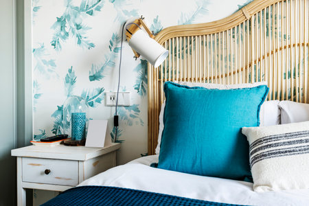 Detail of the bamboo and wicker headboard in a bedroom with blue and white cushions, a wooden...