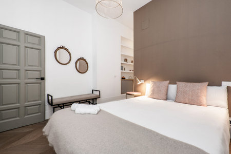 Bedroom with dressing room and en-suite bathroom behind the wall of the king-size bed with reddish cushions and a matching footstoolのeditorial素材