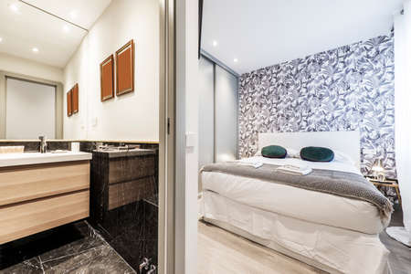 Bedroom with double bed with gray built-in wardrobe, wallpapered walls and en-suite toiletのeditorial素材