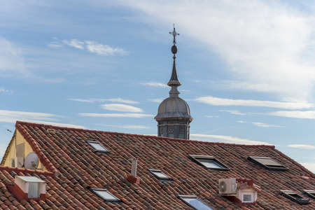View of the tiles of a vintage roof with skylights and a dome in the backgroundの写真素材