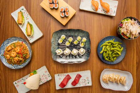 set of asian food dishes with sushi, avocado maki, shrimp noodles, edamame beans, gyozas, norwegian salmon and bao breadの写真素材