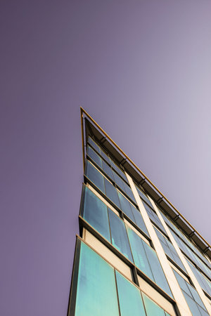 Vertex of a facade of a building with glass cover and a purple sky