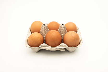 Half a dozen brown eggs in a container or egg cup