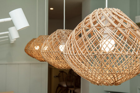 Woven wicker lamps hanging from the ceiling of a room with green wallsの写真素材