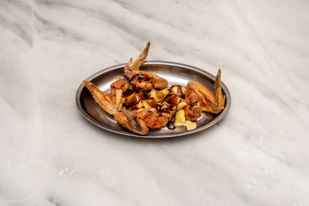 Typical Spanish tapa of fried chicken wings with patatas bravas