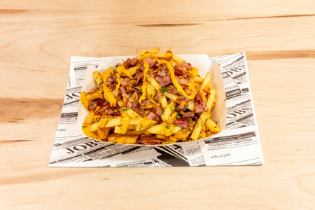 A plate of diced chips with crispy fried bacon, parsley and cheddar sauce