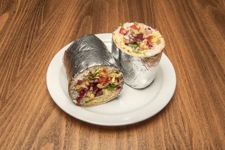 A wonderful burrito stuffed with rice, sautÃ©ed vegetables and red beans wrapped in aluminum foil split in halfの写真素材