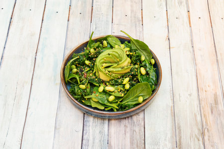 A wonderful vegan salad with spinach, wakame seaweed, edamame beans and a sliced avocado in the...