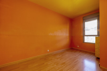Small empty room with brown wooden floor and deep orange painted wallsの写真素材