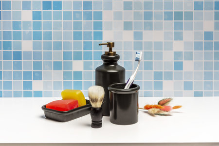 Some red and yellow glycerin soap bars in a black porcelain container, a glass with a brush and a...