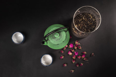 Still life with a green cast-iron teapot, two Japanese porcelain cups, a glass jar with tea and dried rosebudsの写真素材