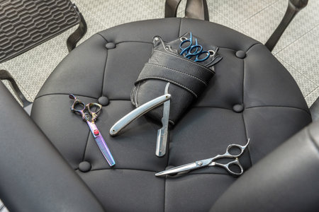 Scissors, epilators, razors and a case for all of them on a black upholstered seatの写真素材
