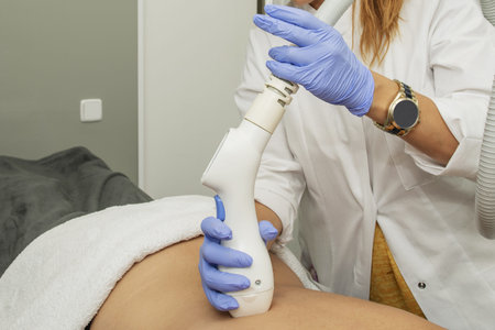 An operator in an aesthetic medicine treatment cabin with electrical devices to apply treatments on...