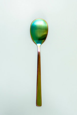 An iridescent metal salad spoon on a smooth surfaceの写真素材