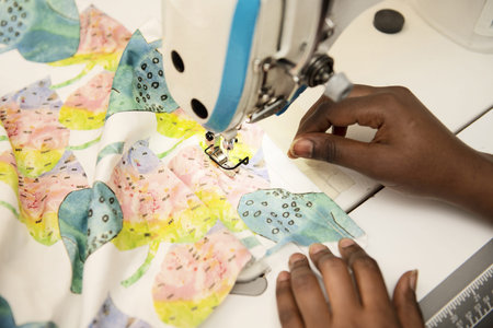 Brown-skinned female worker sewing patterned fabrics with an electric sewing machine