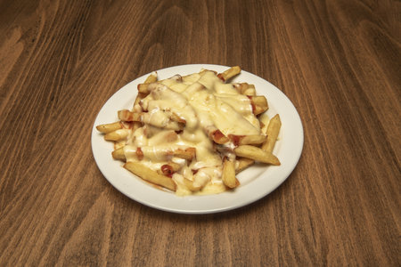 a portion of French fries with lots of melted cheese with fried bacon and ketchupの写真素材
