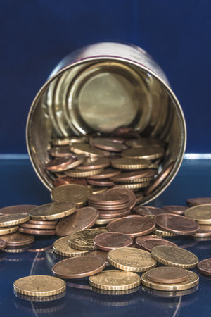 an overturned metal canister full of divisive euro coinsの写真素材