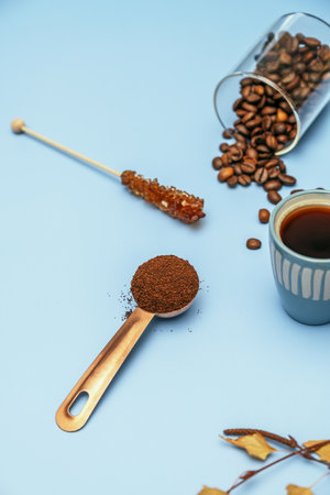 Coffee still life with beans, an espresso, a ladle with ground coffee and an individual coffee pot on a blue tableの写真素材