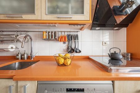 Kitchen with cream wood cabinets paired with orange countertops and orange accents throughoutの写真素材