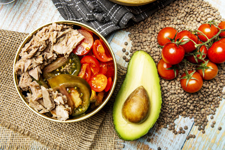 A wonderful canned tuna salad with diced tomatoes and avocados in a golden bowl with pepita tomatoes and avocado over dried lentilsの写真素材
