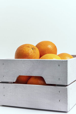 A white colored wooden box sewn together with staples full of delicious ripe orangesの写真素材