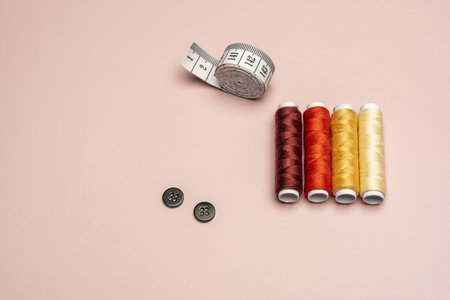 A still life with spools of colored threads with a measuring tape and black buttons