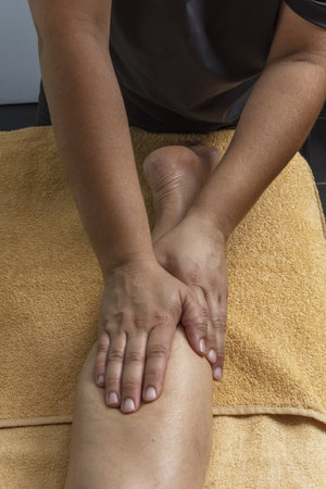 A masseuse applying compression treatments to a patient's calfの写真素材
