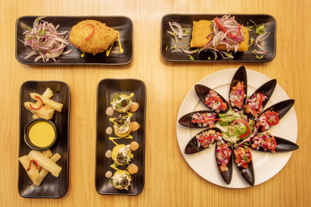 A set of delicious Peruvian food dishes with mussels with pico de gallo, a stuffed tamale, stuffed potato and fried yucca stripsの写真素材