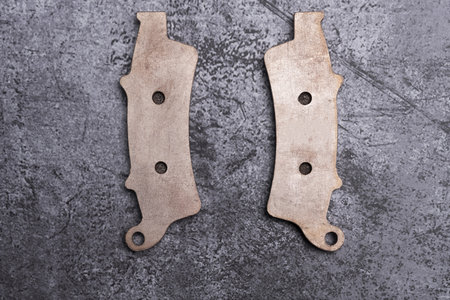 Brand new metallic motorcycle brake pads on a gray surfaceの写真素材