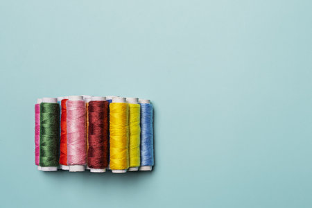 a bunch of spools of colored thread on a smooth blue surfaceの写真素材
