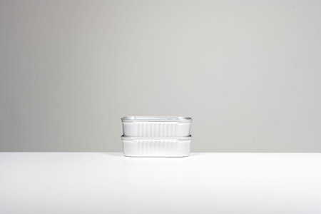 Some simple rectangular shaped metal cans on a smooth white surface