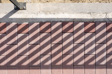 Brown colored paving bricks with shadows from a railingの写真素材