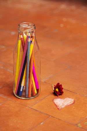 A still life with a glass bottle filled with colored pencilsの写真素材
