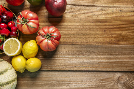 Delicious fruit still life with small lemons, a pomegranate, halved limes, ripe nectarines, some tomatoes on some unvarnished wood planksの写真素材