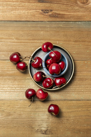 Delicious ripe cherries on a small circular bowls and unvarnished wooden backgroundの写真素材
