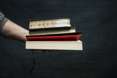 A man's hand holding a few paper books