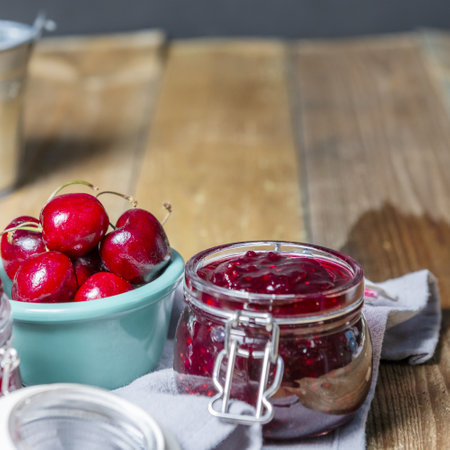 Red fruit jam in a glass jar on kitchen towelsの写真素材