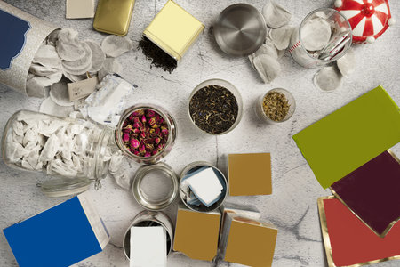 A still life with tea bags in glass jars, tins with lids, loose tea bags, tea in tins