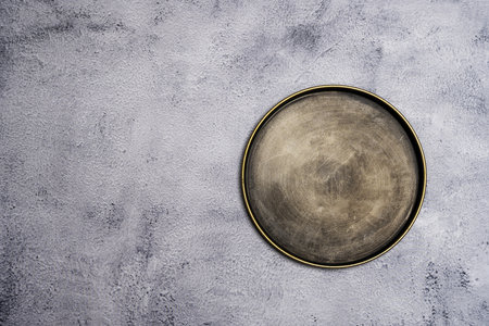 A vintage metal plate with a gold edge on a grainy surfaceの写真素材