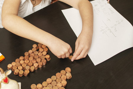 A little girl organizing her saved capital of coins in her piggy bank and counting her fortune